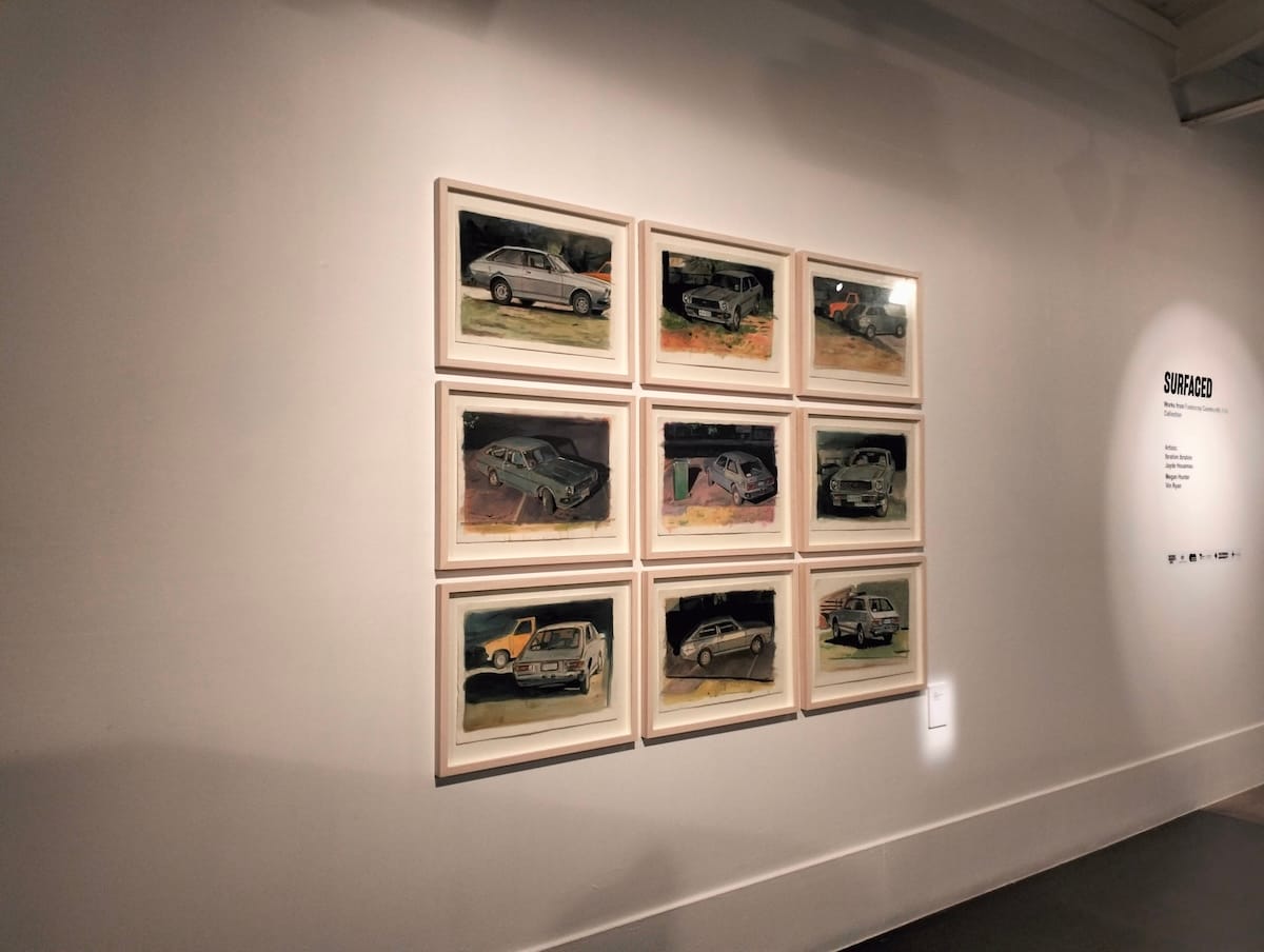 Nine paintings of a 1979 Toyota Corolla on a gallery wall.