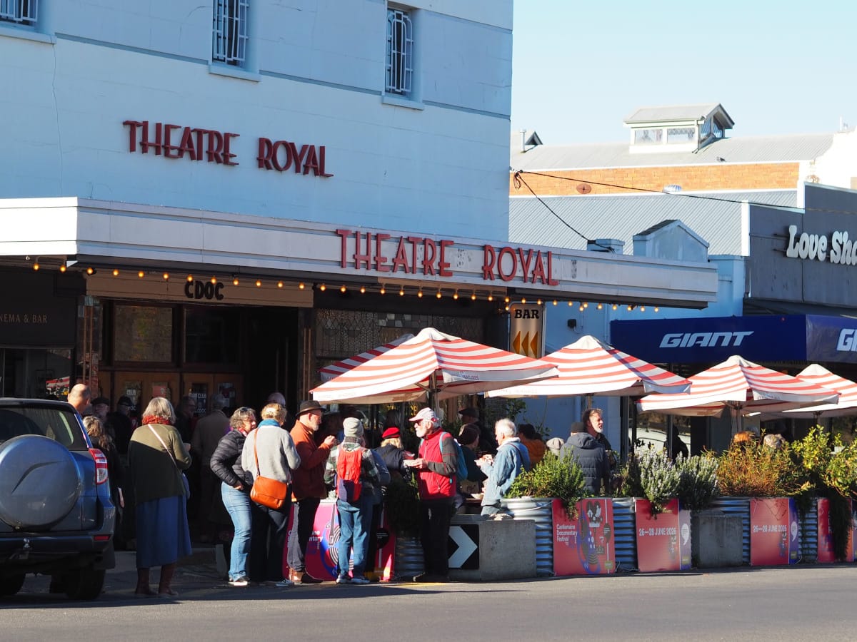 A crowd of people outside the Theatre Royal in the morning sunshine