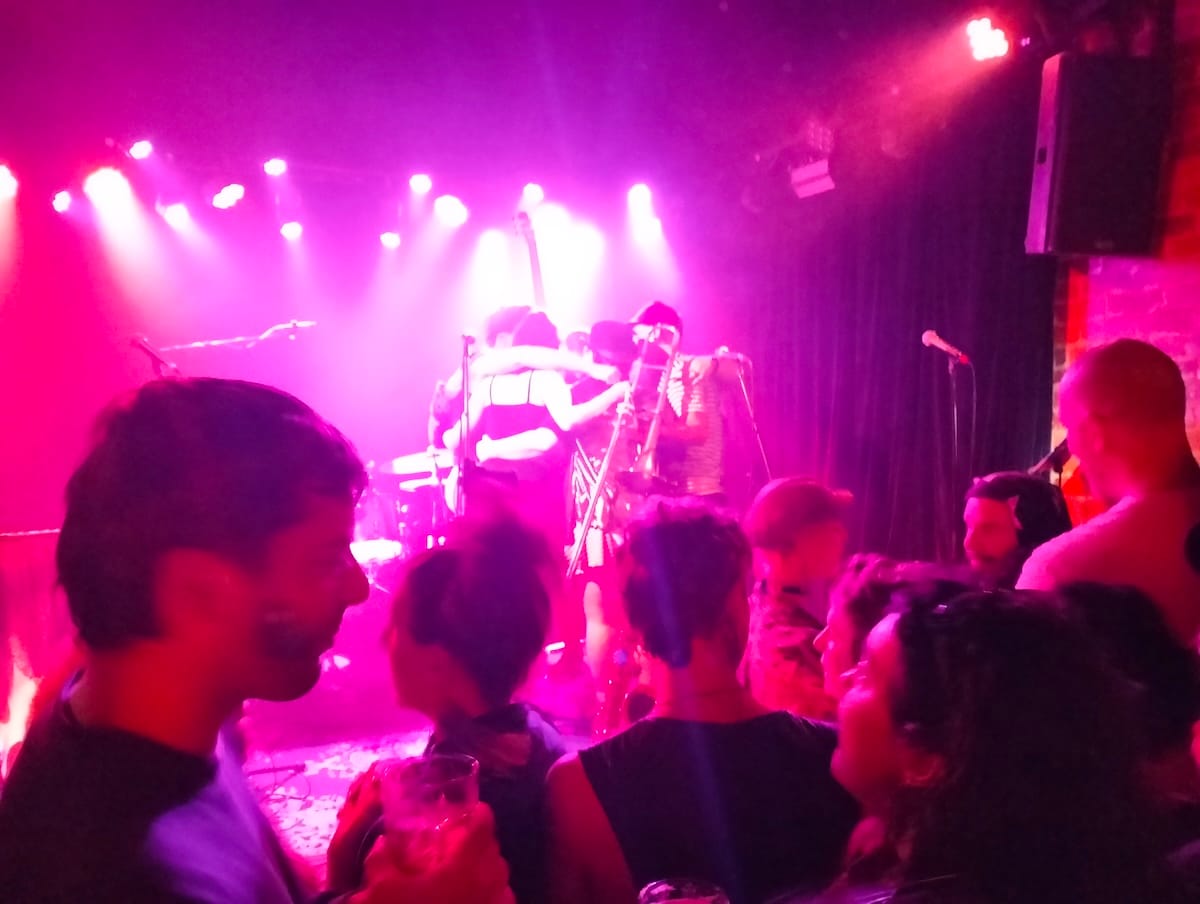 A band huddling on stage with people in the crowd in the foreground.