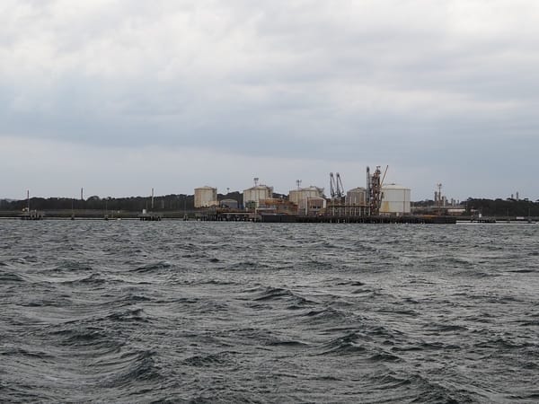 An oil refinery in a bay. The water is choppy.