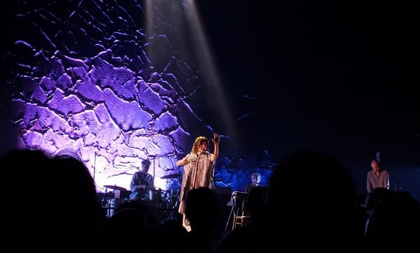 PJ Harvey and band on stage.