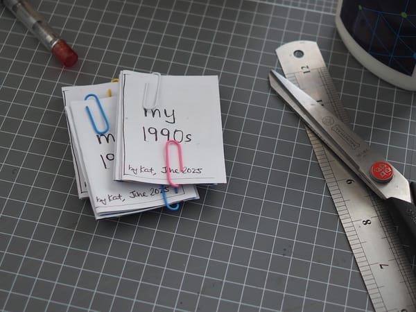 A small pile of small zines with paperclips holding them while glue dries