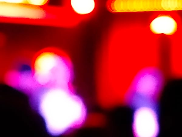 A very blurry photo of people on stage lit by red and purple stage lighting