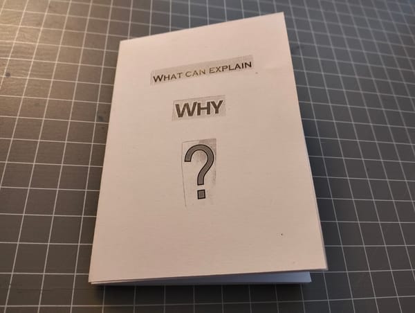 A folded paper zine with the title 'what can explain why?'