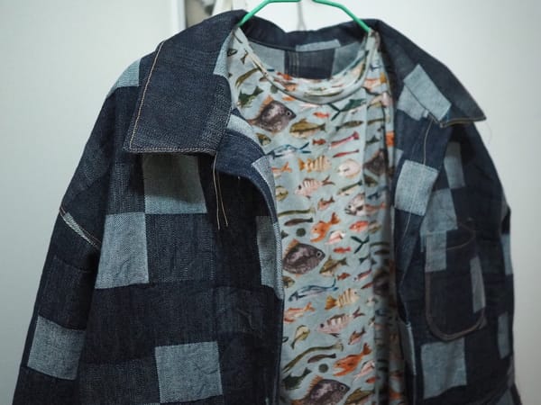 A denim coat hanging over a fish shirt.