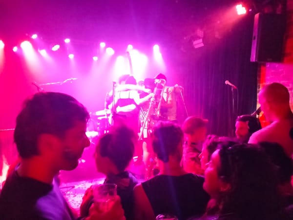 A band huddling on stage with people in the crowd in the foreground.